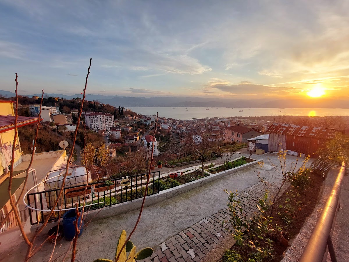 Golden sunset over the Bay of İzmit, with city lights beginning to glow and ships on the water.
