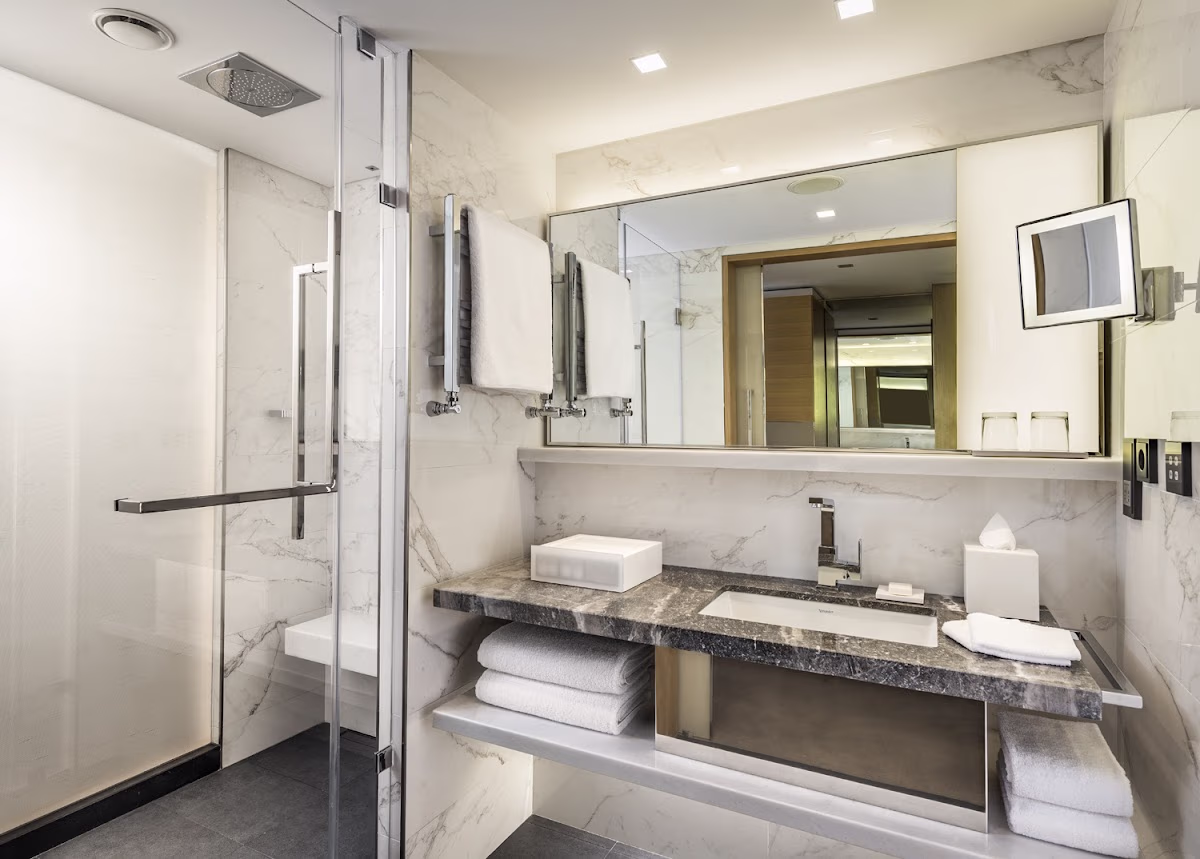 Mermer kaplı lüks Swissotel banyosu, duş ve lavabo alanı.