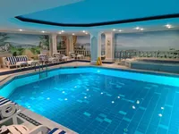 Miran unutarnji bazen u palači Çırağan Kempinski, s plavom ambijentalnom rasvjetom, klasičnim stupovima i zidnim muralima.