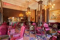 Elegantni Orient Bar u hotelu Pera Palace s plišanim magenta stolicama, klasičnim drvenim šankom i raskošnim lusterima.