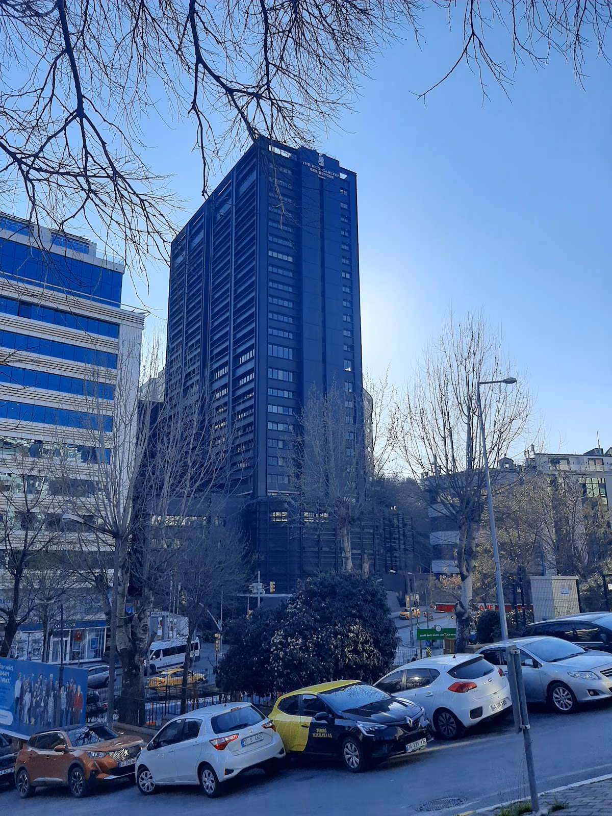 从绿树成荫的街道望去，伊斯坦布尔丽思卡尔顿公寓引人注目的深色现代外观。