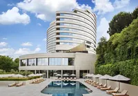 Conrad Istanbul Bosphorus hotel exterior with its iconic curved design and outdoor swimming pool surrounded by greenery.