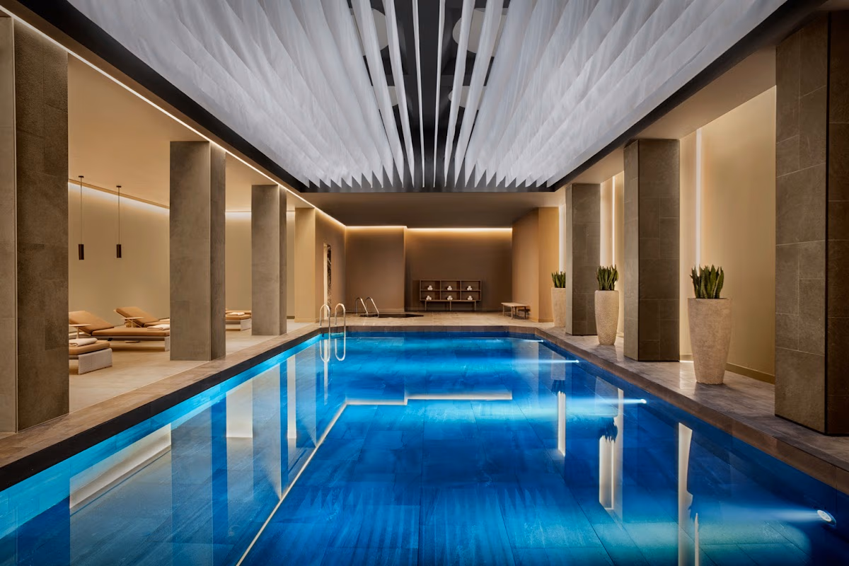 Η γαλήνια εσωτερική πισίνα στο σπα του Conrad Istanbul Bosphorus, με βαθιά μπλε νερά και μοντέρνες αρχιτεκτονικές λεπτομέρειες.