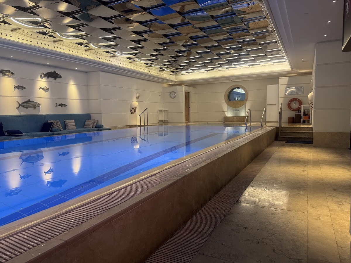 Modern indoor swimming pool at Divan Istanbul with mirrored ceiling and fish decor.
