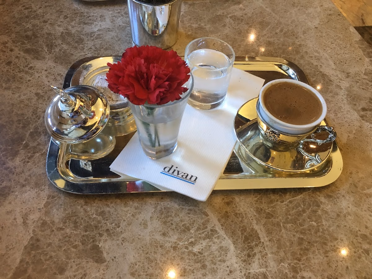 Traditional Turkish coffee served on a silver tray with Turkish delight and a red flower.