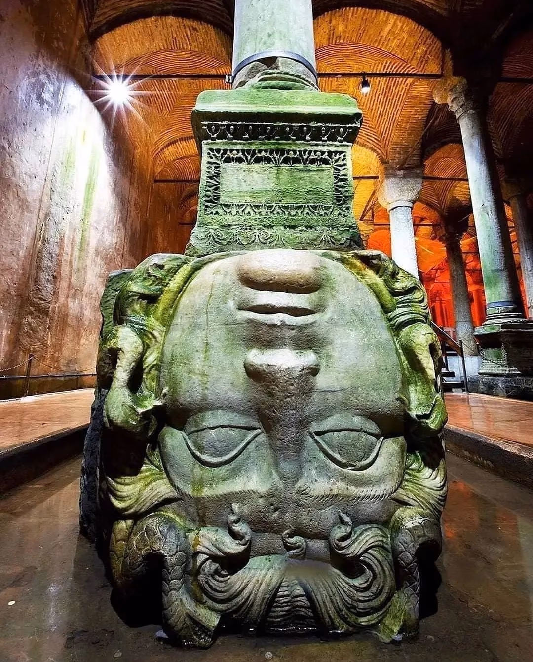 Upside-down Medusa head statue and ancient column base in Basilica Cistern.