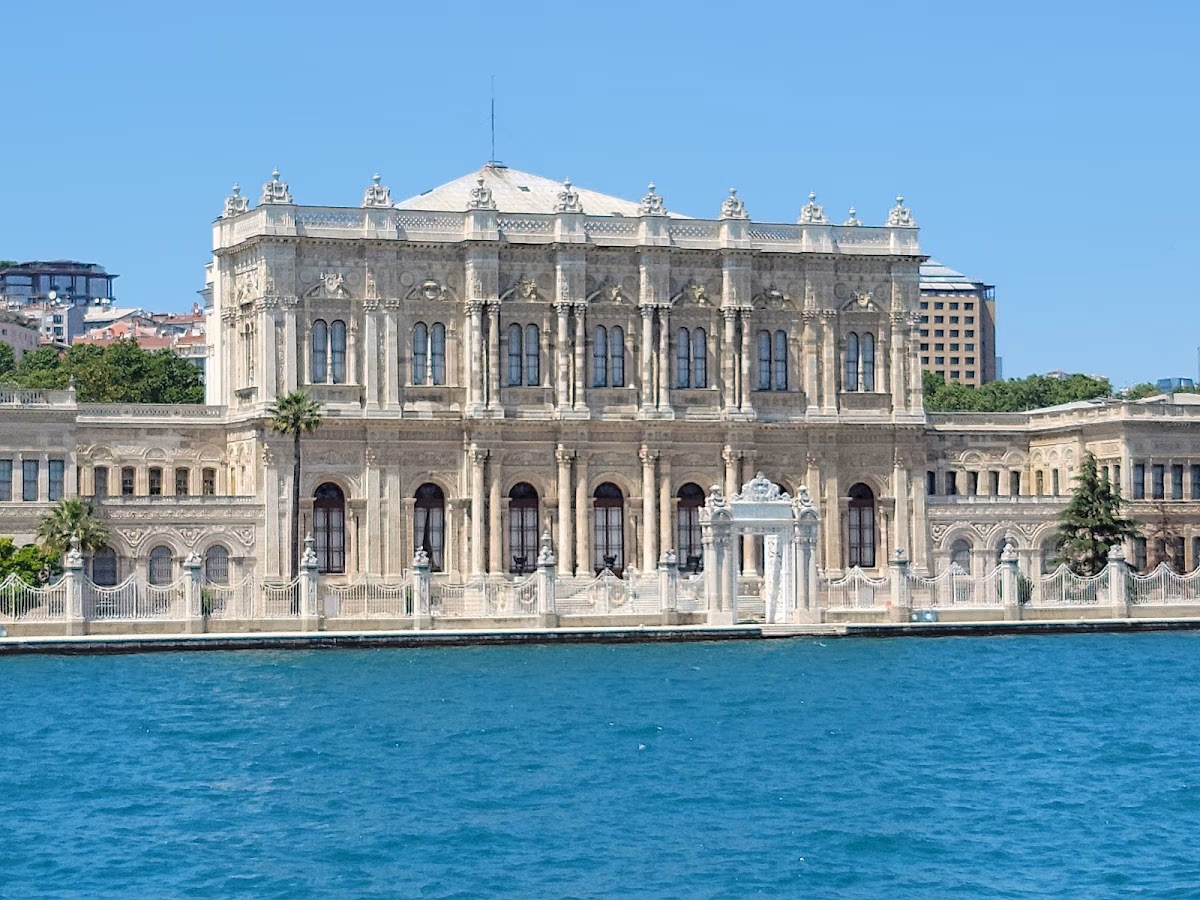 Außenansicht des Dolmabahçe-Palastes vom Bosporus aus mit Marmorsäulen und Meerblick.