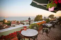 Rooftop terrace of Hotel Dersaadet Istanbul with marble tables, flowers, and Marmara Sea view.