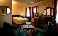Traditional Ottoman-style bedroom at Hotel Dersaadet Istanbul with green armchairs and a yellow bed.