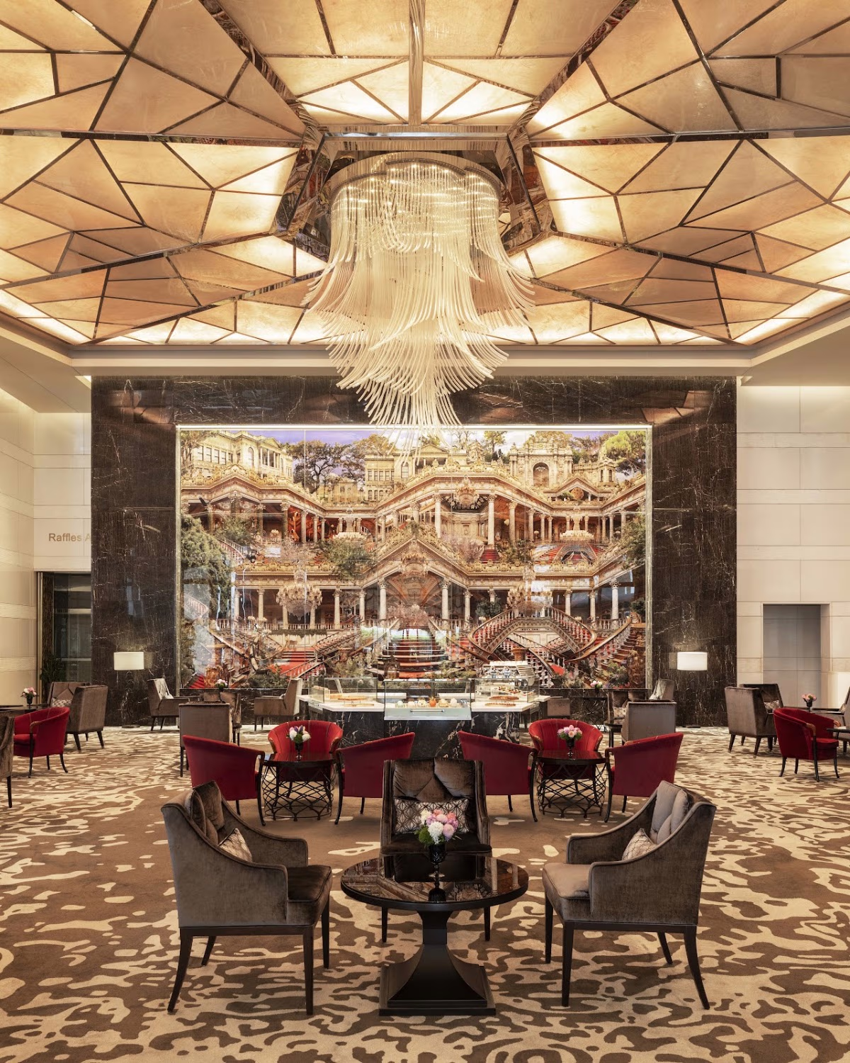 Raffles İstanbul'un görkemli avizeli, saray tablolu ve şık koltuklu lüks lobi salonu.