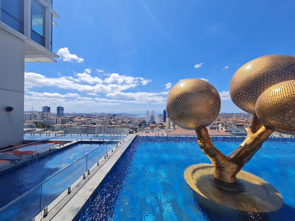 Rooftop infinity pool with a golden tree sculpture overlooking the Istanbul skyline under a blue sky