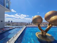 Rooftop infinity pool with a golden tree sculpture overlooking the Istanbul skyline under a blue sky