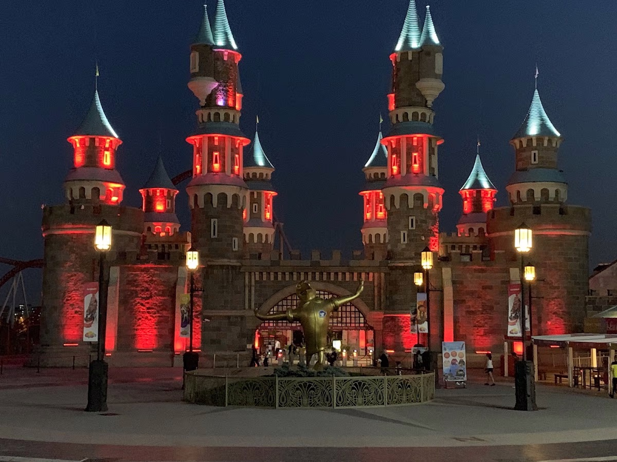 Fairytale castle illuminated in red light at night in Vialand Theme Park.