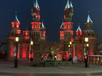 Fairytale castle illuminated in red light at night in Vialand Theme Park.