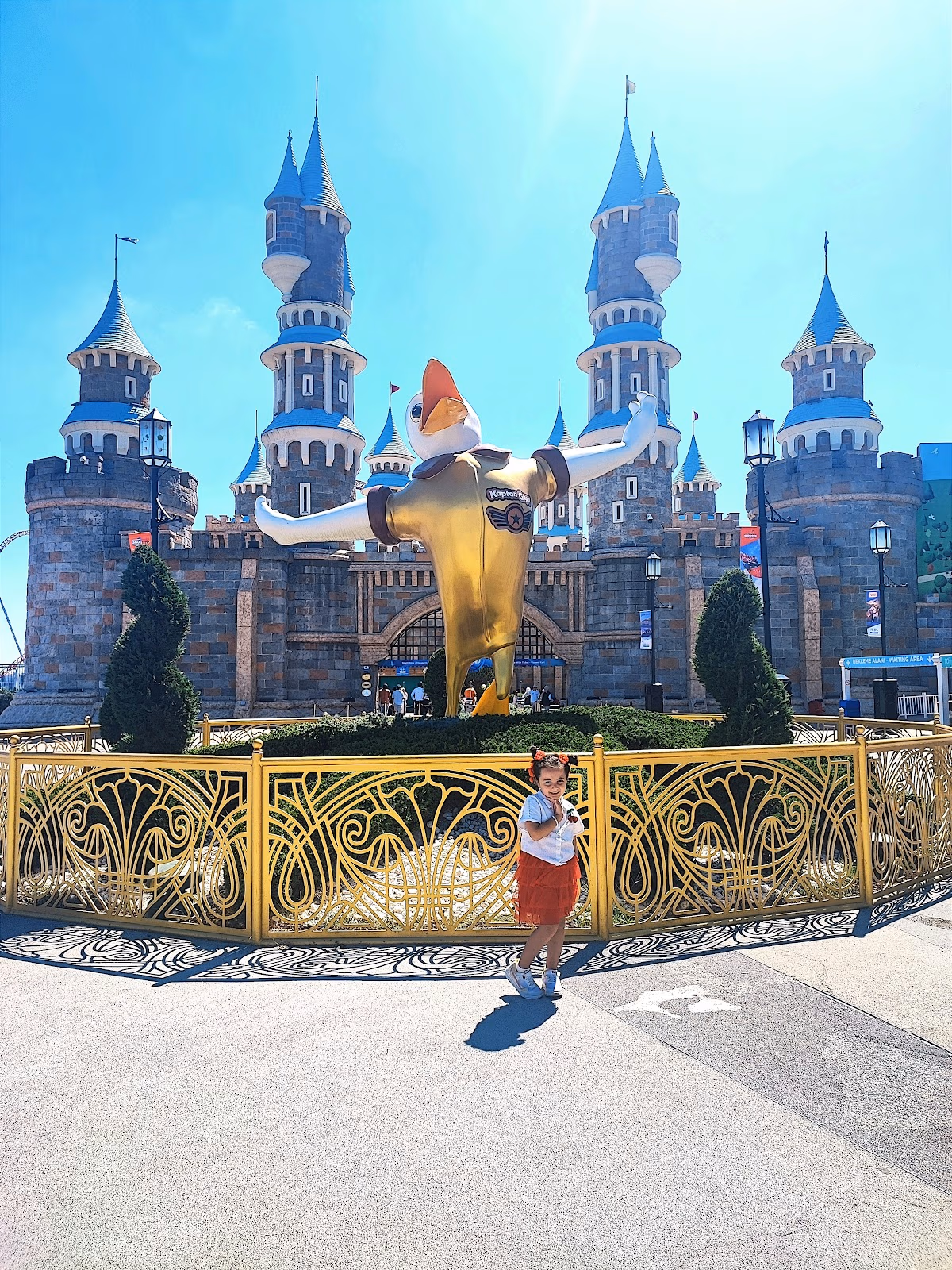 Girl in front of a golden duck statue and fairy tale castle at Vialand Theme Park.