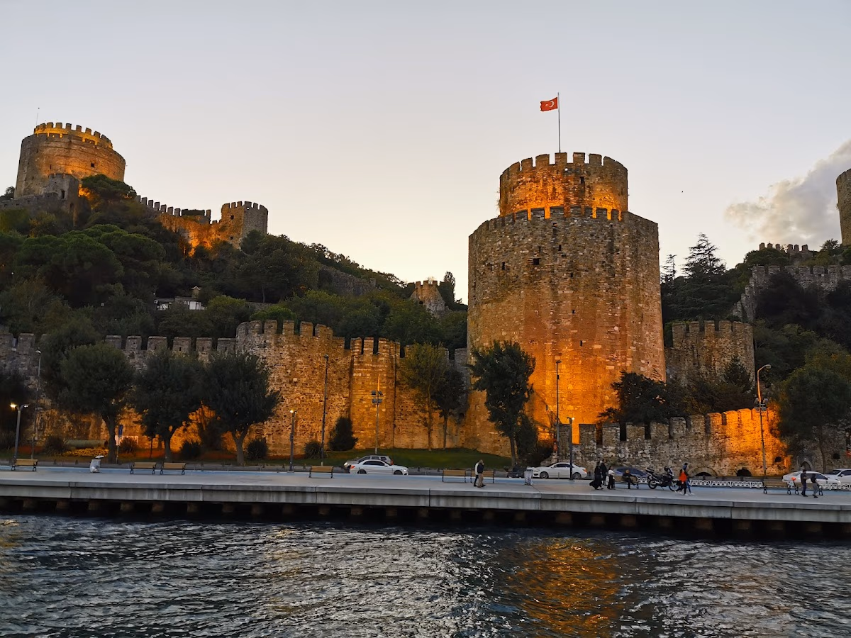 Gün batımında ışıklandırılmış Rumeli Hisarı kuleleri ve sahil yolu.