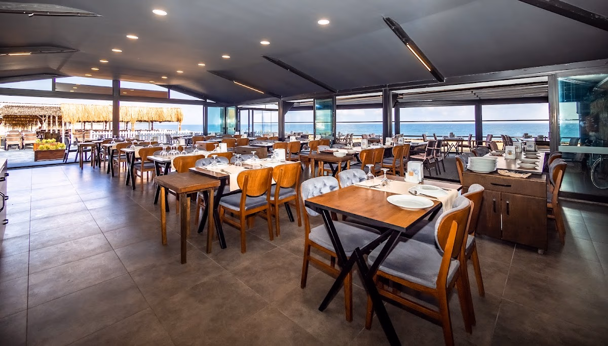 Marin Beach Hotel'in modern dekora ve okyanusa bakan panoramik pencerelere sahip geniş kapalı yemek alanı.