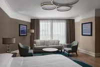 İstanbul Marriott Hotel Pendik'teki geniş bir süitte kanepe ve modern koltukların yer aldığı şık oturma alanı.