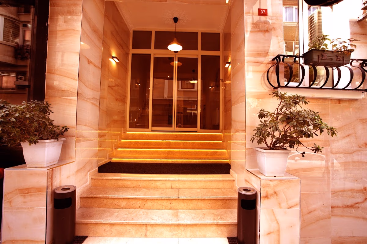 The warmly lit marble entrance and glass doors of MLS Şişli Hotel, creating a welcoming and elegant first impression.
