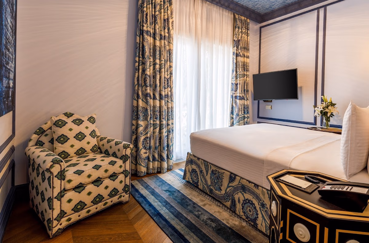 Luxury hotel room at Hagia Sophia Mansions with traditional patterned armchair and bed runner.