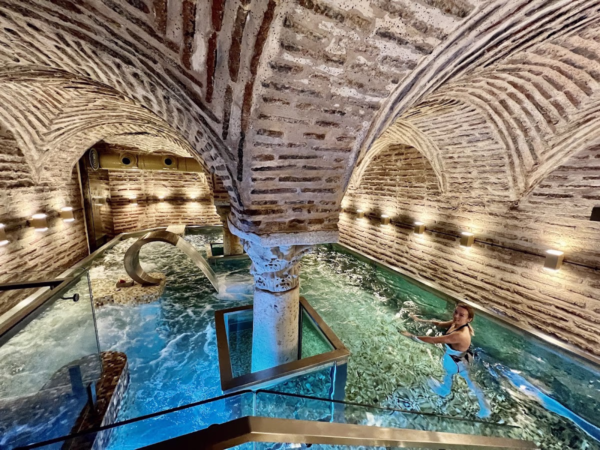 A guest swimming in the indoor pool of Hagia Sophia Mansions with historical brick vaults and columns.