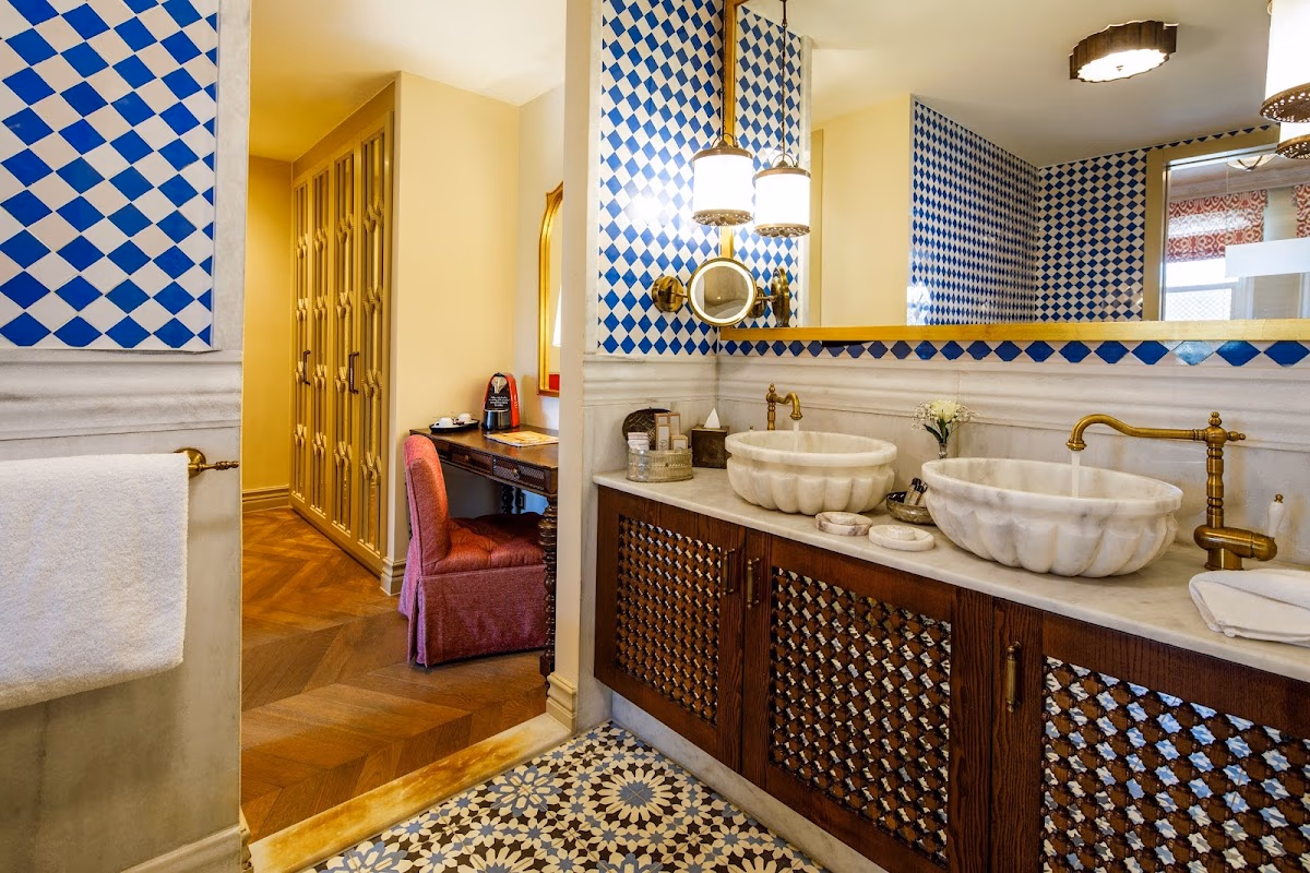Marble sinks, gold faucets, and blue-white checkered walls in a Hagia Sophia Mansions bathroom.