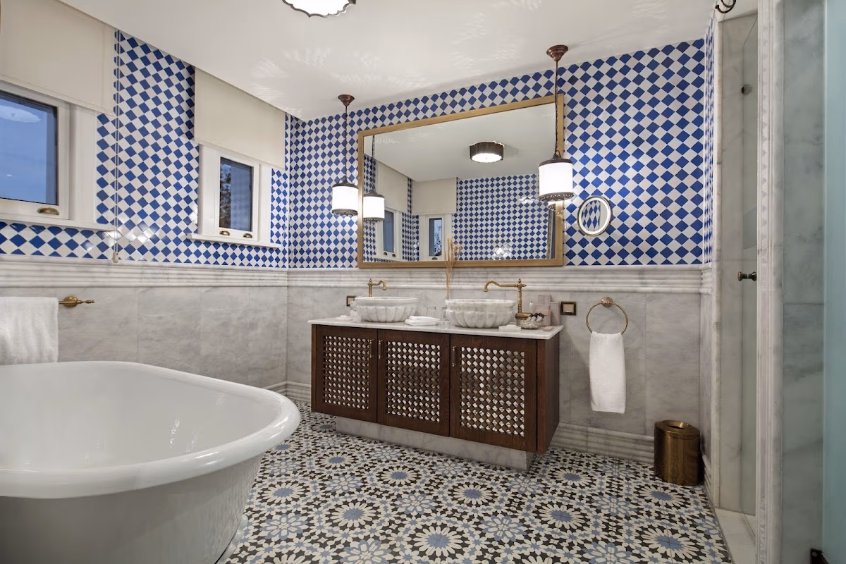 Luxury hotel bathroom with a large bathtub, marble floors, and blue-white checkered walls.
