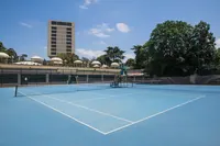 Blue tennis courts at Hilton Istanbul Bosphorus with hotel tower in background.