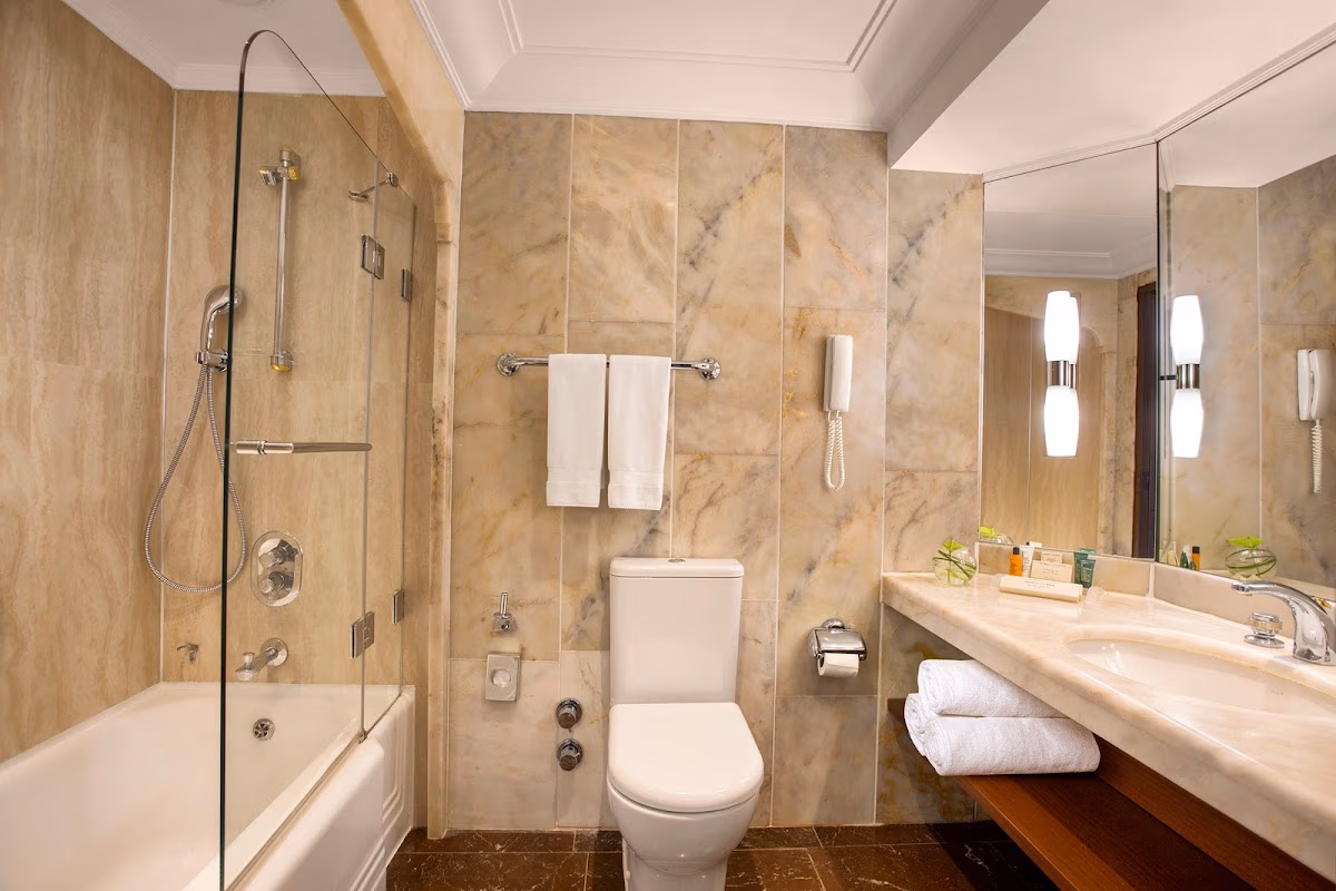 Hilton İstanbul Bosphorus'taki modern tuvalet ve cam duşakabinli küvet içeren şık mermer banyo. Elemen Transfer.