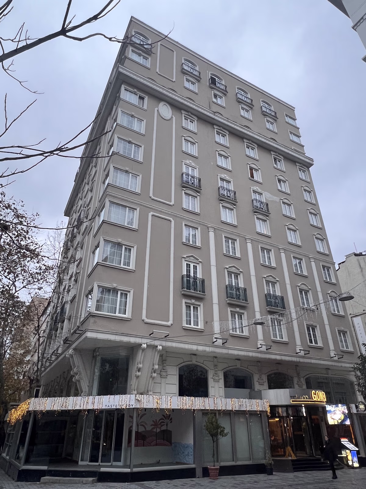 Taksim Gönen Otel'in klasik mimariye sahip, çok katlı bej renkli dış cephesi, bulutlu bir günde.