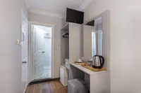 Hotel room entrance area with mini bar, kettle, and bathroom door view.