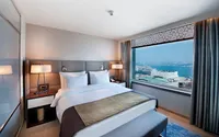 Modern otel odası, büyük yatak ve panoramik İstanbul Boğazı manzaralı pencere.