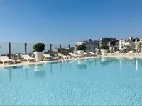 Şehir manzaralı açık yüzme havuzu ve güneşlenme şezlongları.
