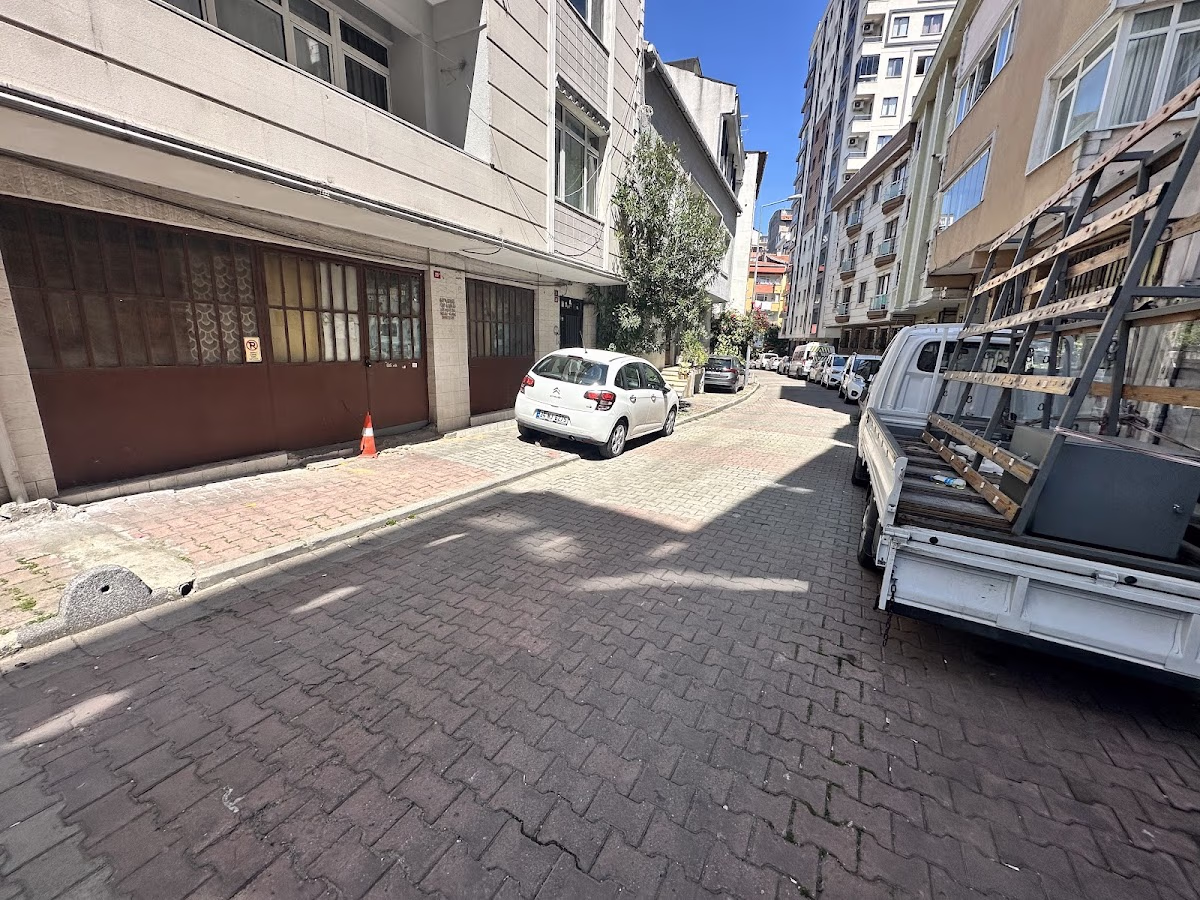 A narrow street with parked cars near Beyaz Konaklar. Explore the area with Elemen Transfer.