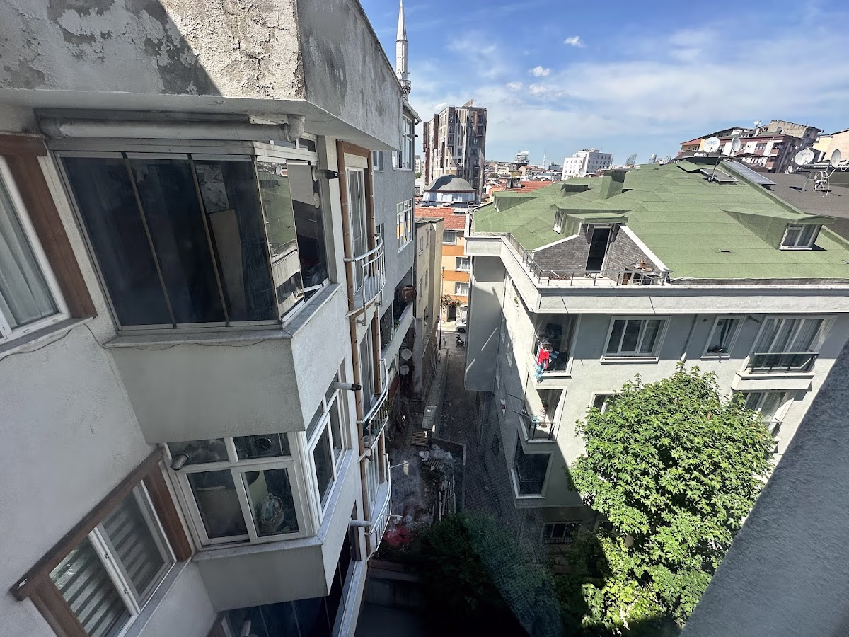 View from Beyaz Konaklar of a narrow passage between buildings, with a minaret in the distance.