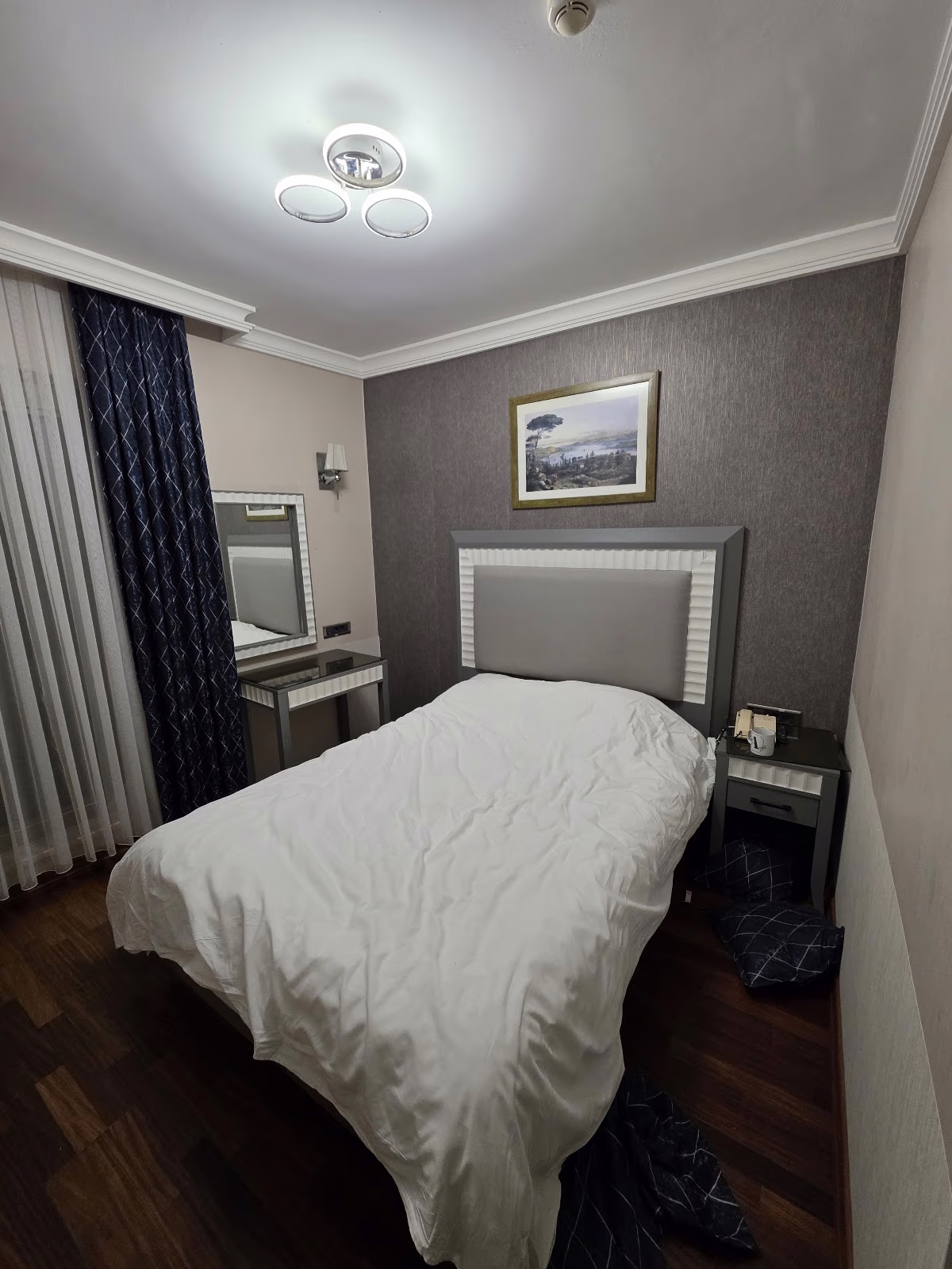 Taksim Stare Hotel'de beyaz yorganlı çift kişilik yatak, makyaj masası ve duvarda çerçeveli bir tablo bulunan konforlu yatak odası.