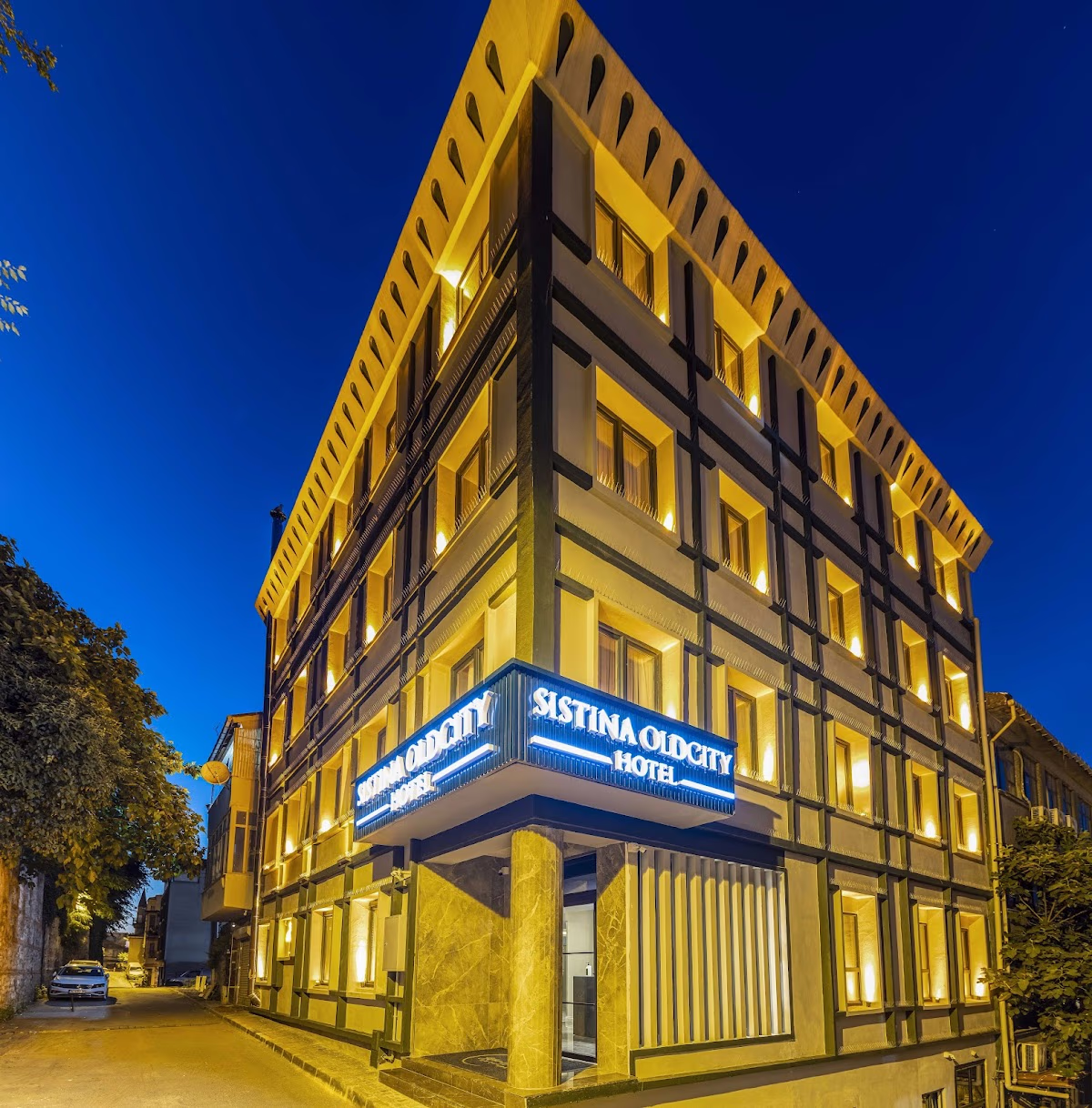 Gece aydınlatılmış Sistina Old City Hotel'in dış cephesi. Elemen Transfer'in premium filosu ile şık bir varış.