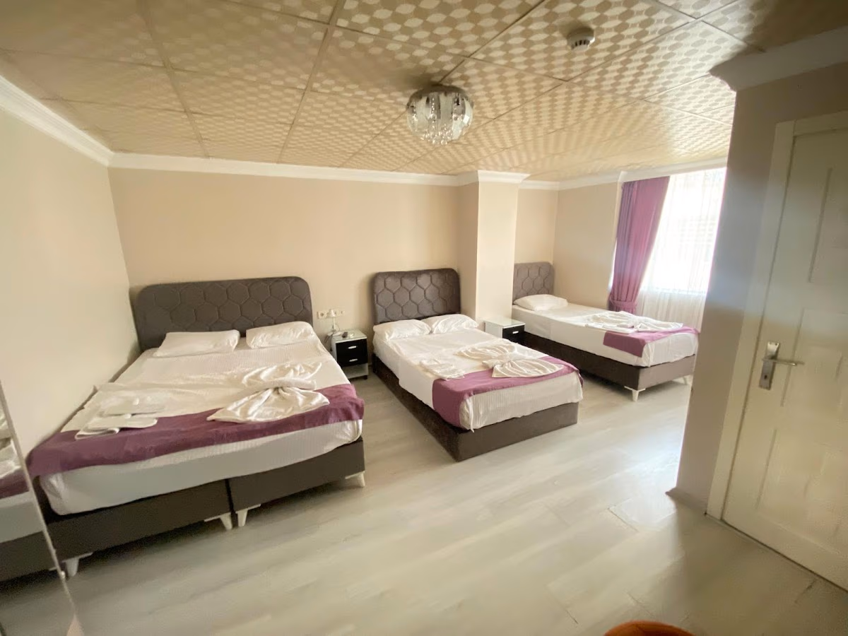 A spacious and bright family room at Bağcılar Kümbet Otel with two double beds and one single bed.