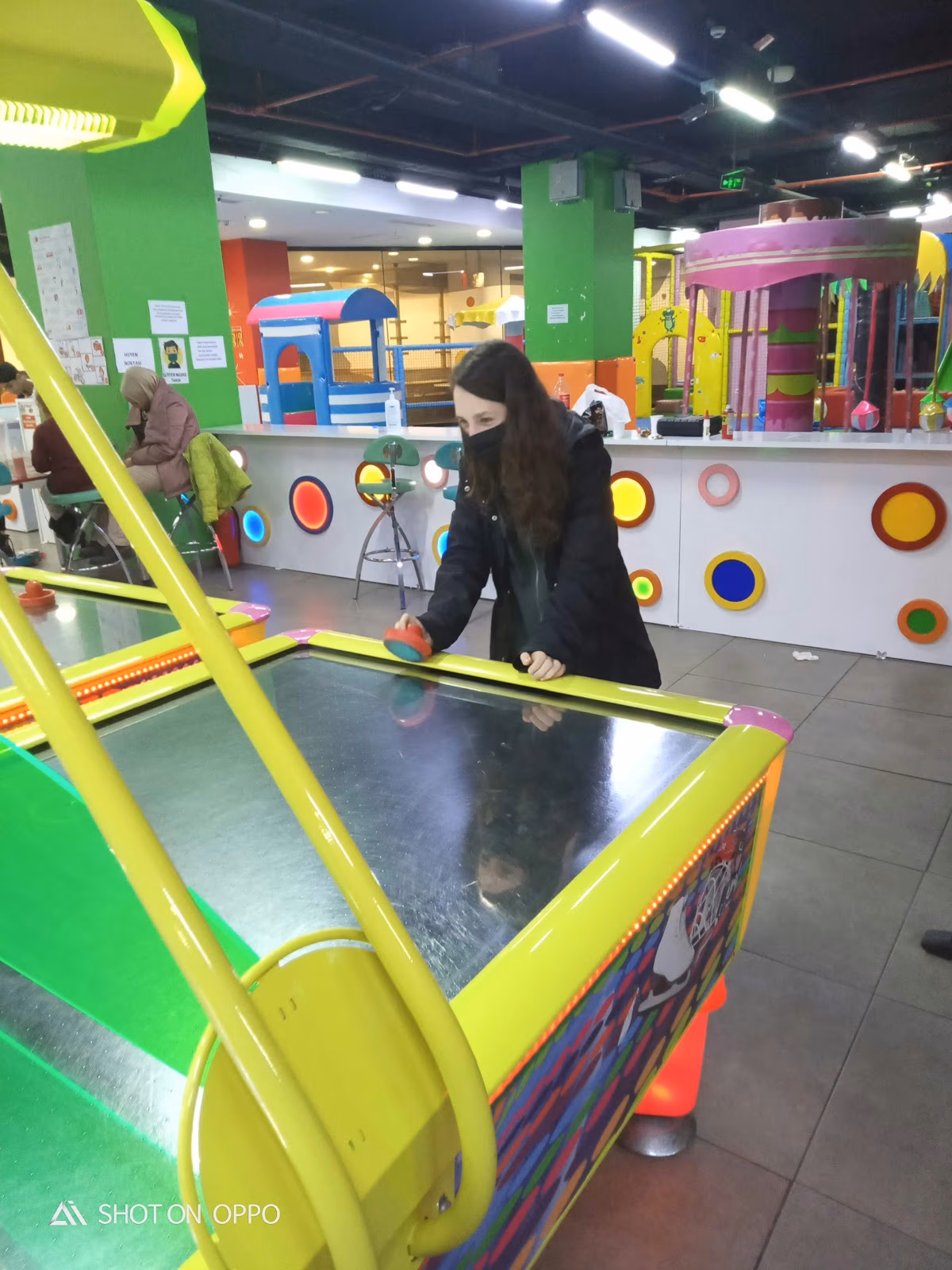 Güngören Park AVM'deki oyun alanında hava hokeyi oynayan bir kadın, renkli ve eğlenceli bir aktivite.